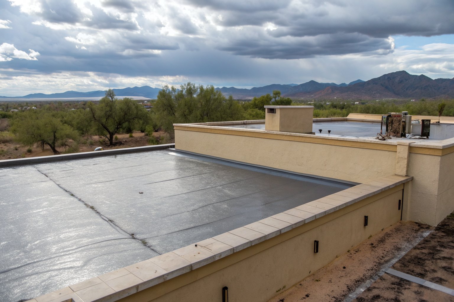 Rainwater ponding on a flat roof membrane behind a stucco parapet after a summer storm